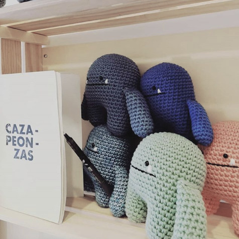 Vista lateral de cinco muñecos de punto junto a un catálogo de Cazapeonzas